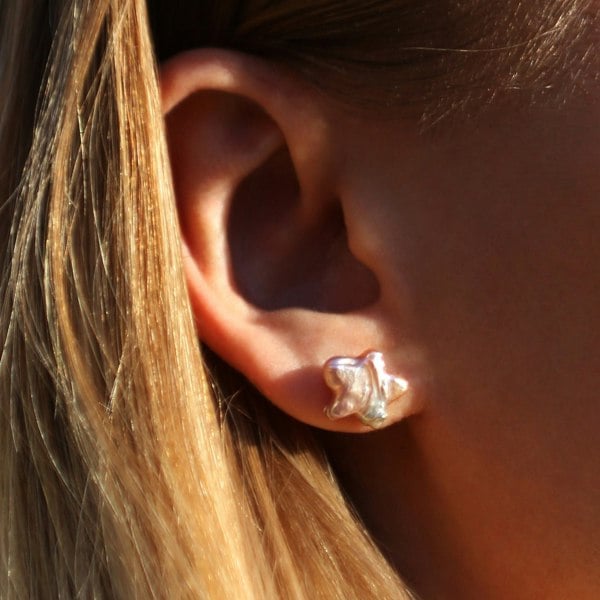 Close up of an ear with pink star-shaped pearl studs.