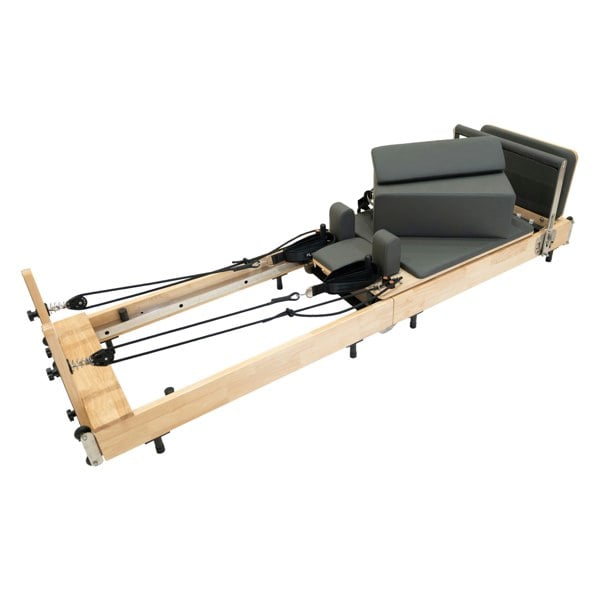 Pilates reformer machine in oak wood with gray padded cushions, adjustable springs, and a sleek, modern design for effective workouts