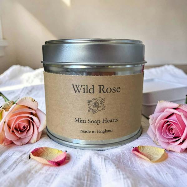Tin of Wild Rose Mini Soap Hearts with pink roses and rose petals on a white fabric background
