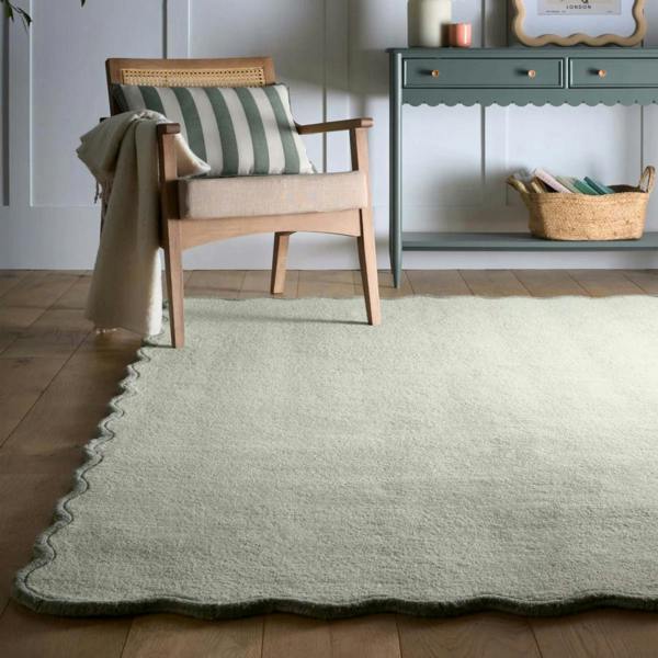 Green rug on a wooden floor with a chair and cabinet in the background