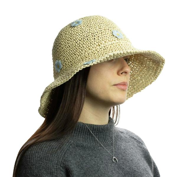 Beige straw sun hat with light blue daisy appliques, worn on head with dark hair