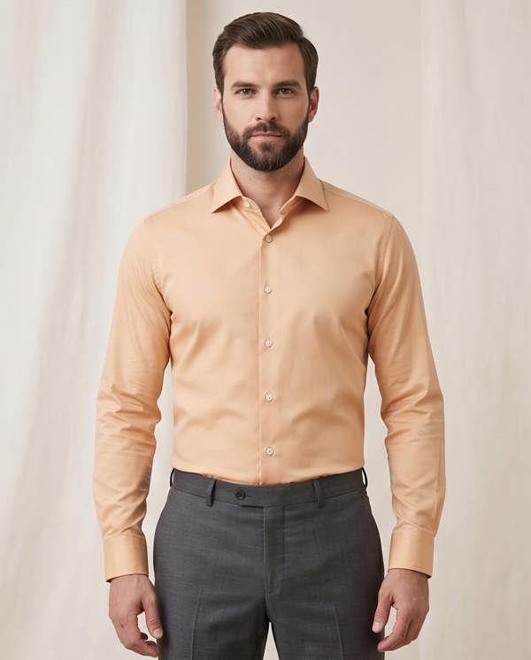 Man wearing a peach-colored dress shirt and gray pants against a plain background
