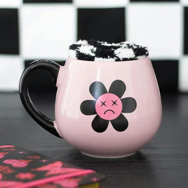Pink ceramic mug with black handle, sad flower face graphic, fuzzy rim fill