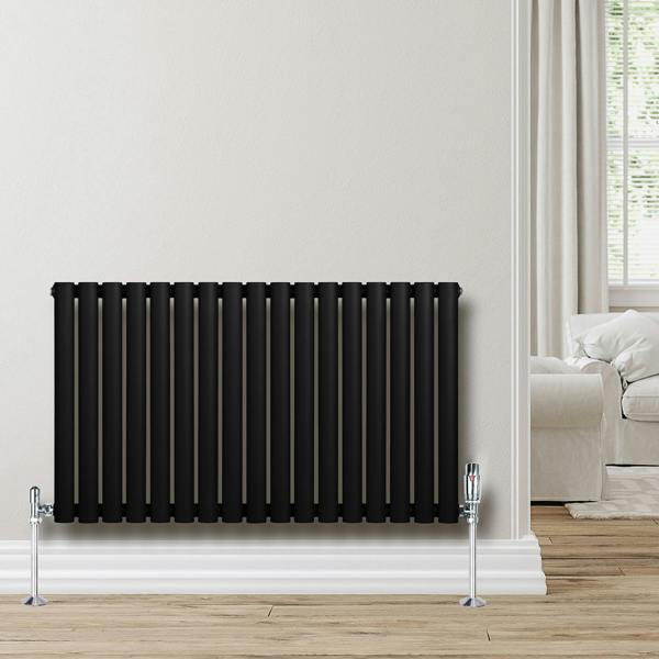 Sleek black oval single column radiator with chrome valves, mounted on a light wall, complementing a cozy living room setting