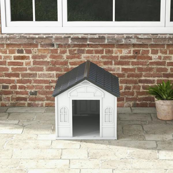 White plastic dog house with grey sloped roof and front entry door on patio