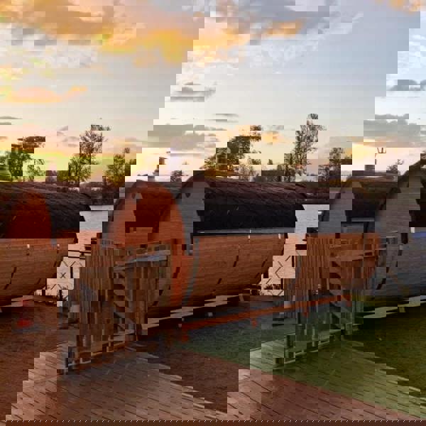 Wooden barrel saunas by the water at sunset