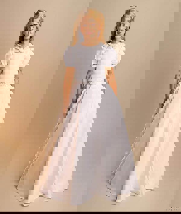 Young girl wearing a white dress with a plain background