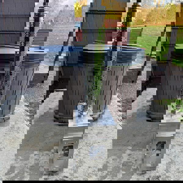 Wood-fired hot tub on a wooden platform with a scenic sunset over mountains and fields.