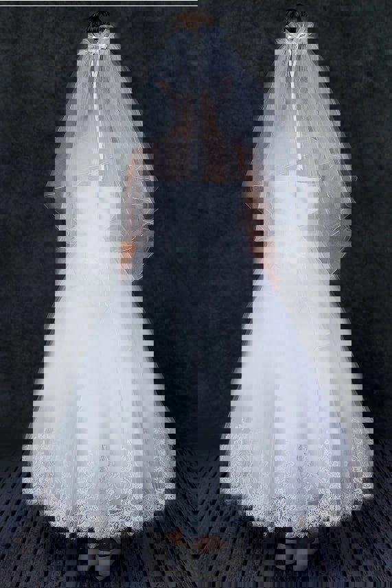 White communion dress with a veil on a dark background