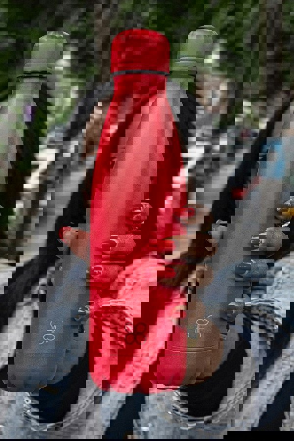 Lady holding red metal flask bottle to screen