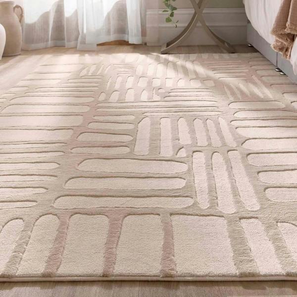 Beige patterned rug on a wooden floor with a blurred background