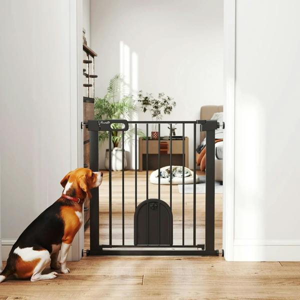 Black pet safety gate with cat flap, vertical bars, and dogs near the doorway