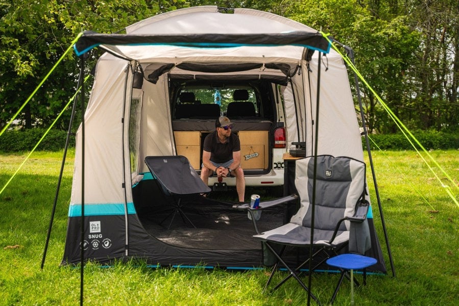 A man sat on the tailgate of A volkswagen T5 inside his snug poled's tunnel shot from the front