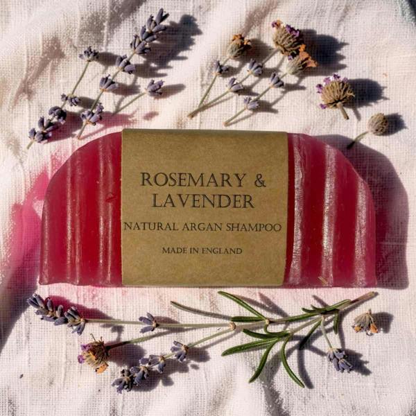 Bar of soap labeled 'Rosemary & Lavender' with lavender flowers on a textured fabric background