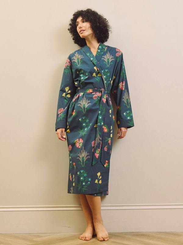 Woman wearing a navy blue floral patterned robe against a beige wall.