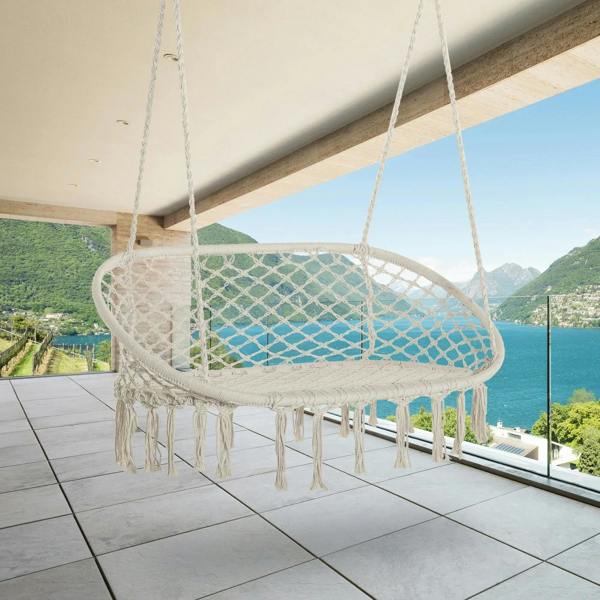 Cream hanging macrame hammock chair with oval net seat and long fringe tassels