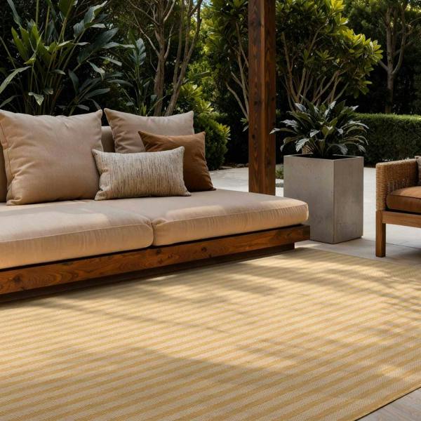Outdoor seating area with a beige sofa, cushions, and a yellow striped rug.