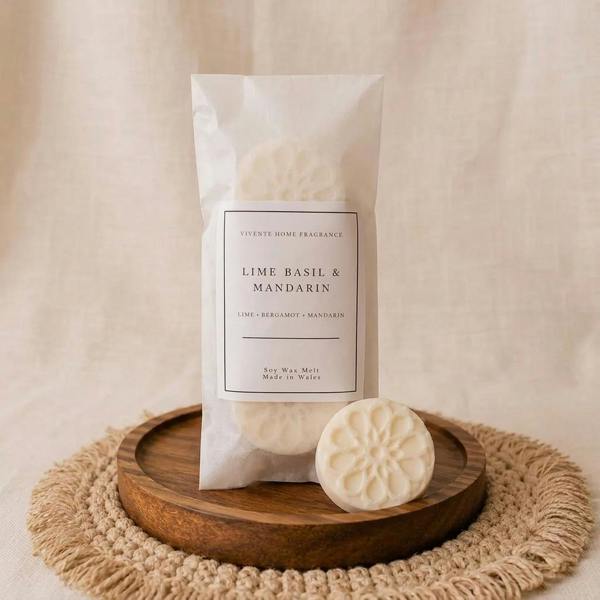 Lime, Basil and Mandarin soy wax melt and paper pouch on a simple wooden dish against a soft linen background by Abode Home & Gifts
