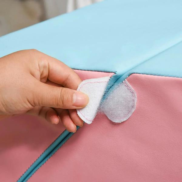 Hand fastening a pink and blue fabric patch on a foam climber edge