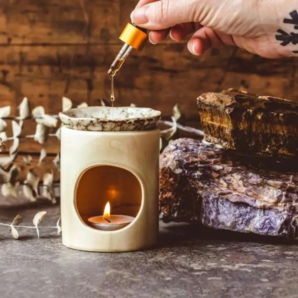 Handmade crackled cream ceramic oil burner lit with a tea light while fragrance oil is dropped into the removable marbled dish by Abode Home & Gifts