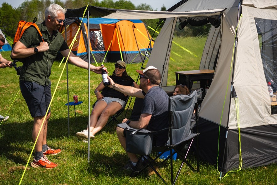 A group of people relaxing outside of the Cubo XL Motorhome Awning - Fibreglass Poles that is attached to a Crafter.