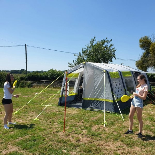 An image of two females playing swing ball outside of the OLPRO Home 5 Berth Inflatable Family Tent.