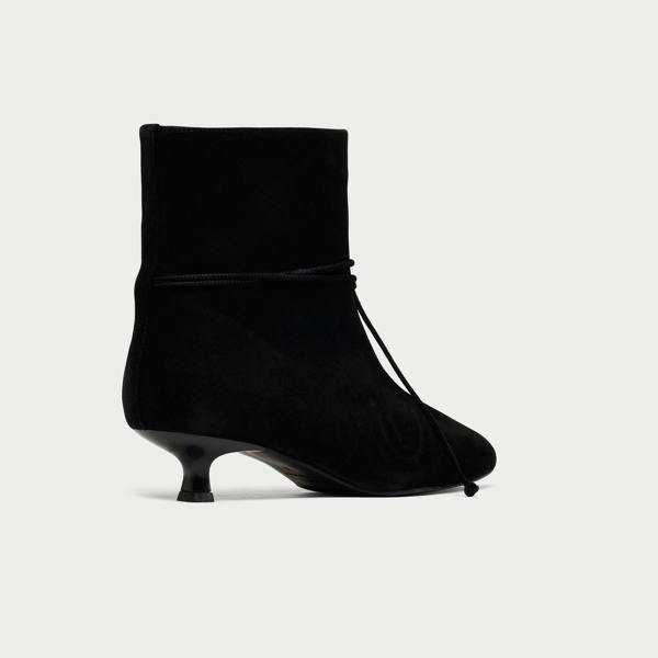 Black ankle boot with a kitten heel on a light gray background