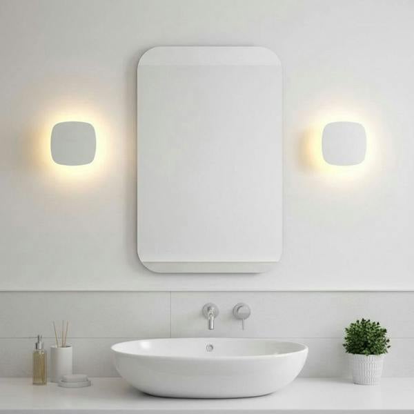 white bathroom wall mount light fixture mounted on the wall either side of a mirror in the bathroom 