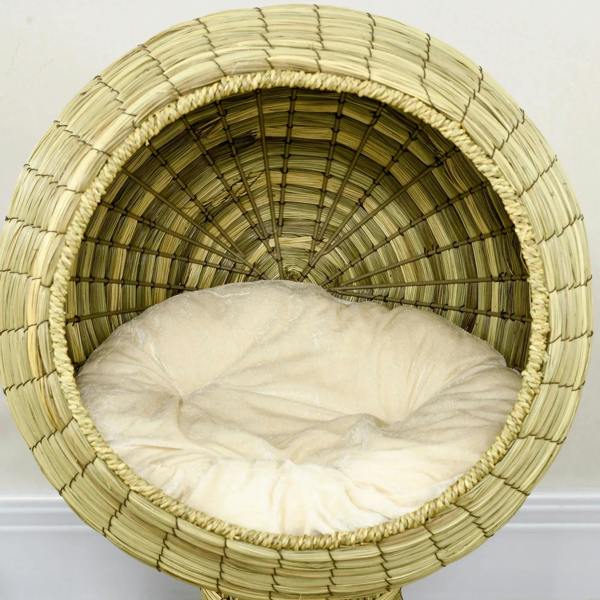 Close-up of circular cat bed tunnel with cream cushion inside, natural yellow woven