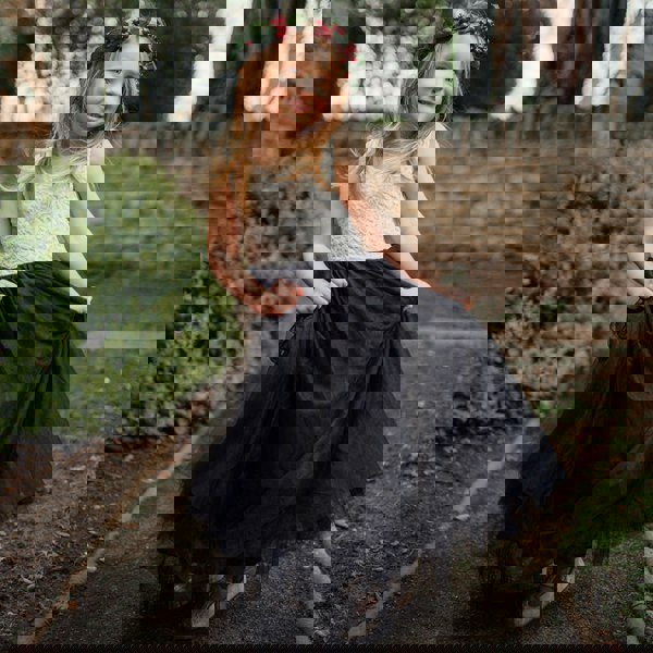 Young girl in a lace top and black skirt with a floral headband outdoors.