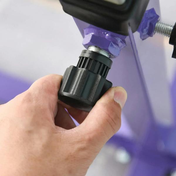 Hand tightening the height clamp on a purple adjustable gymnastics bar post
