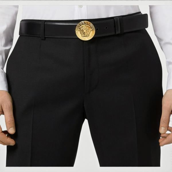 Supplied Fashion black leather belt featuring a round gold Medusa head buckle worn with tailored trousers and shirt