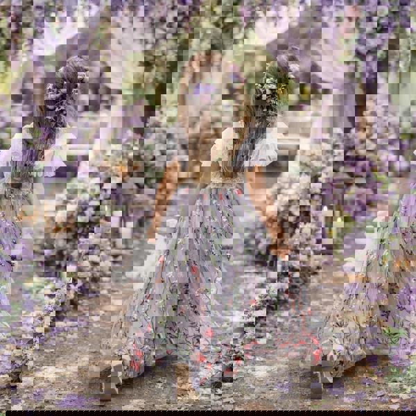 Young girl in a floral dress walking through a beautifully decorated outdoor setting with flowers and lanterns.