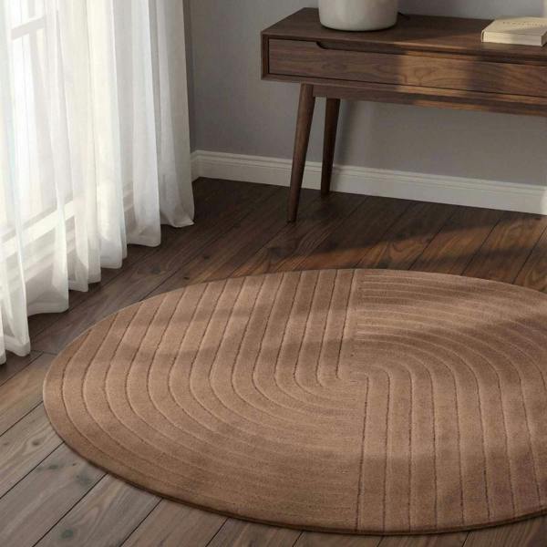 Round brown rug on a wooden floor with a wooden console table in the background.