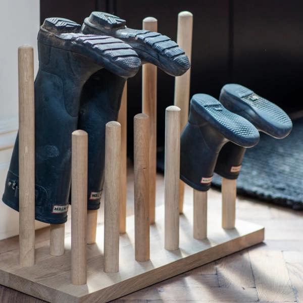 A large solid oak welly stand holding six pairs of boots in a double row inside a bootroom by Abode Home & Gifts.