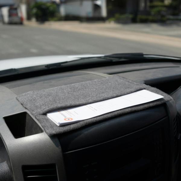 Smoke grey storage pouch made of soft felt, neatly holding documents on a vehicle dashboard, showcasing its practical design