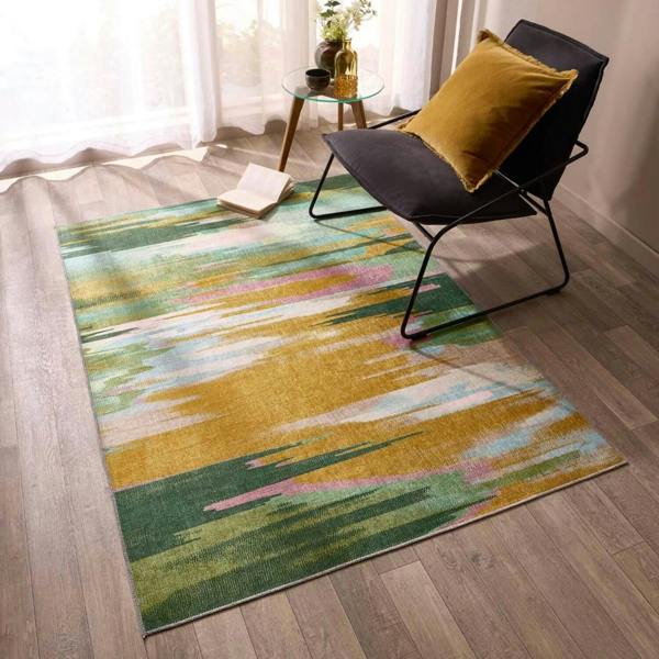 Multicolored abstract rug on a wooden floor with a chair and small table in the background.