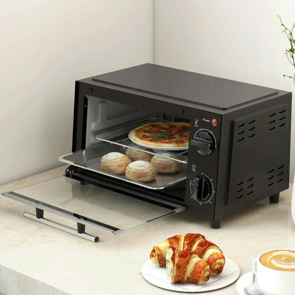 Black mini toaster oven with glass door open, baking tray extended and food inside.