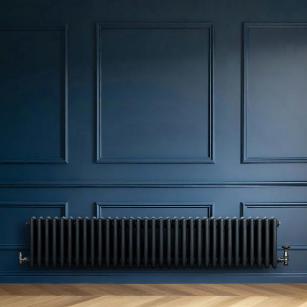 Traditional anthracite 4 column radiator, 300 x 1505mm, featuring a sleek, matte finish against a deep blue wall and wooden floor