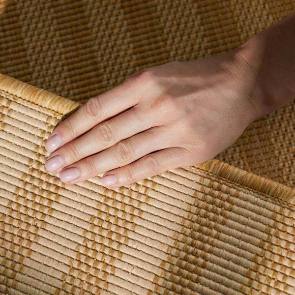 Hand resting on a woven mat with a warm color palette
