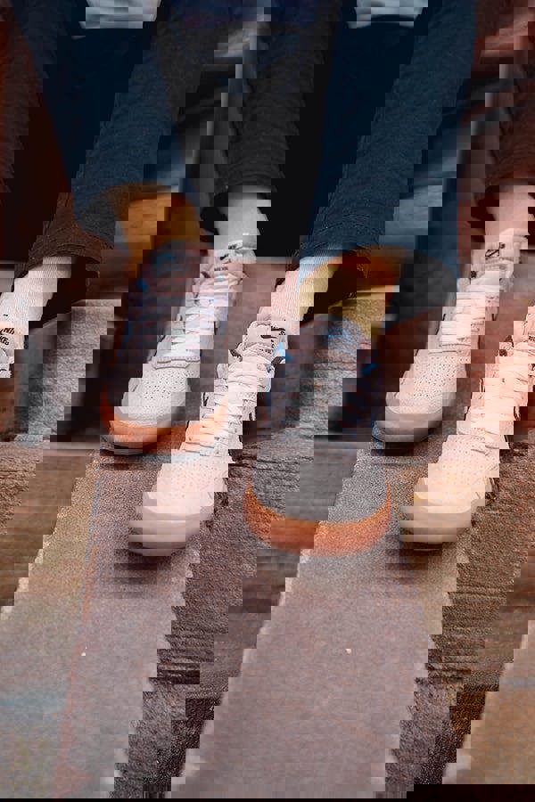 Yellow Socks and White sneakers with brown soles worn by a person sitting on steps.