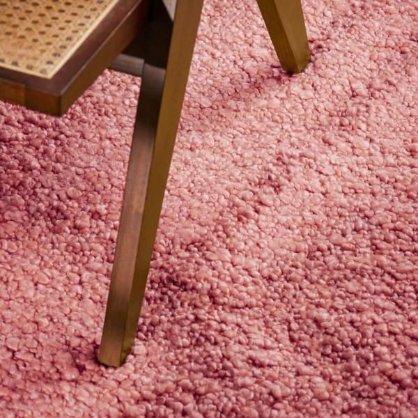 Close-up of a pink carpet with a chair leg visible