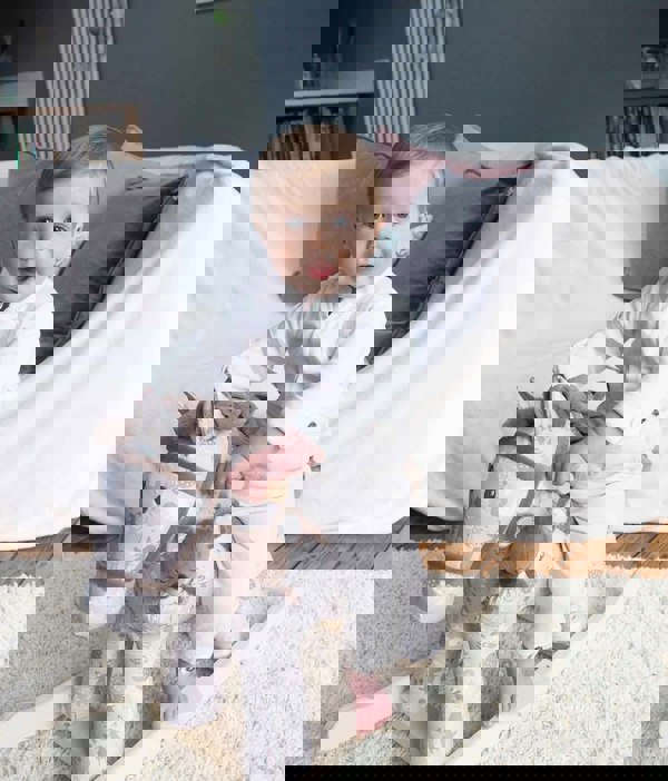 Little boy riding Biscuit & Skip Rocking Horse with supportive wooden handles and footplates