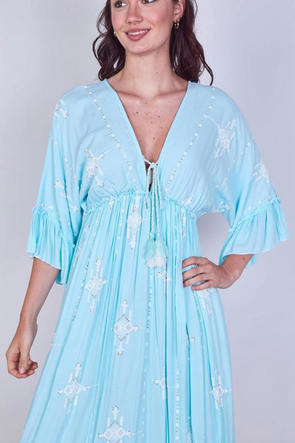 Woman wearing a light blue dress with star patterns on a plain background