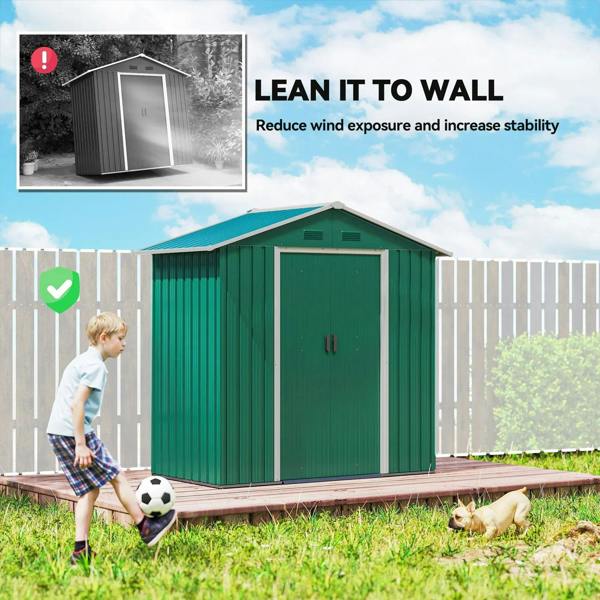 Green metal shed set up against a fence with doors facing forward