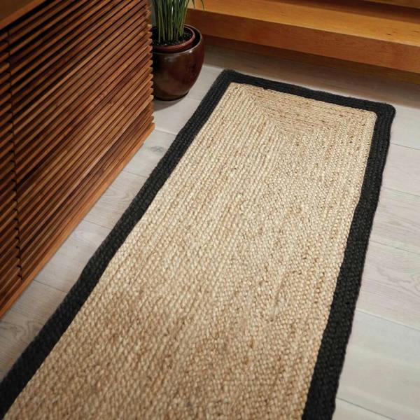 Beige jute rug with black border on a wooden floor