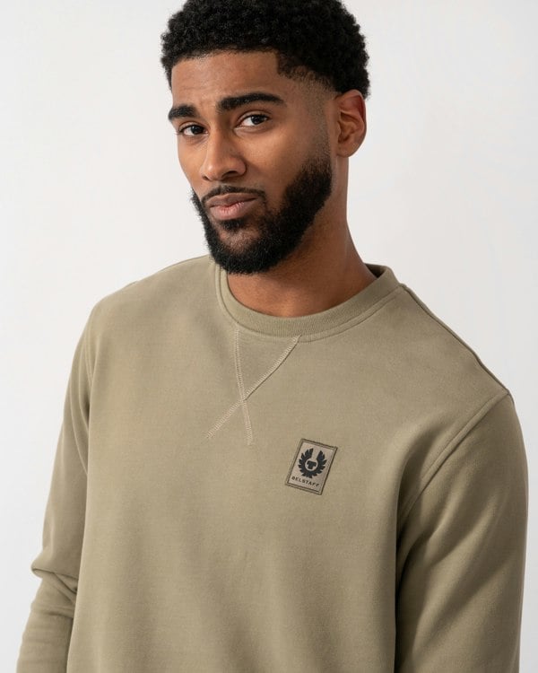 close up of a model wearing a Belstaff Mens Crew Neck Sweatshirt With Logo Patch in Fatigue Green