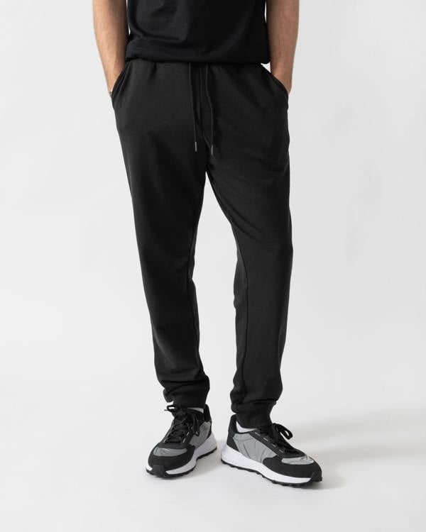 studio shot of a model wearing Tommy Hilfiger Mens Track Joggers in Black