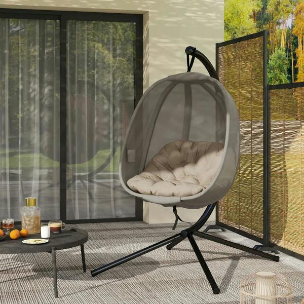 Hanging egg chair on black stand with khaki mesh pod and beige cushion on patio