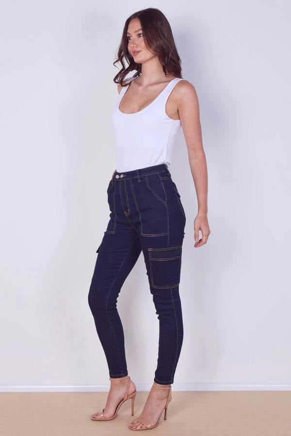 Woman wearing dark blue jeans and a white top on a plain background